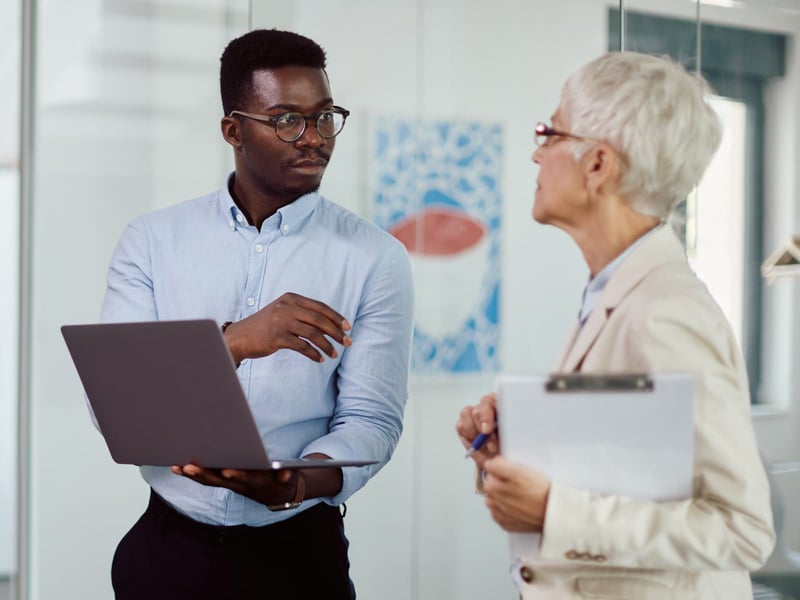 Young male colleague consults with older female colleague