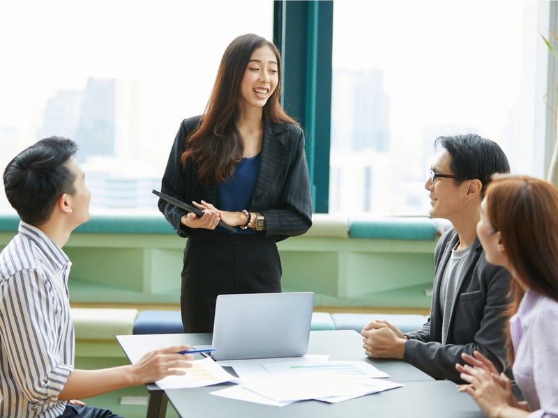 Business woman giving presentation to table of colleagues